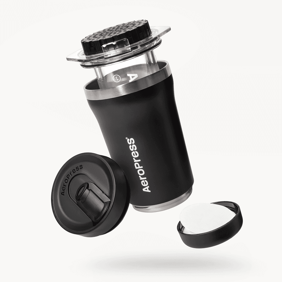 Vista explosionada de cafetera AeroPress Go negra con vaso, émbolo, tapa y filtros de papel.