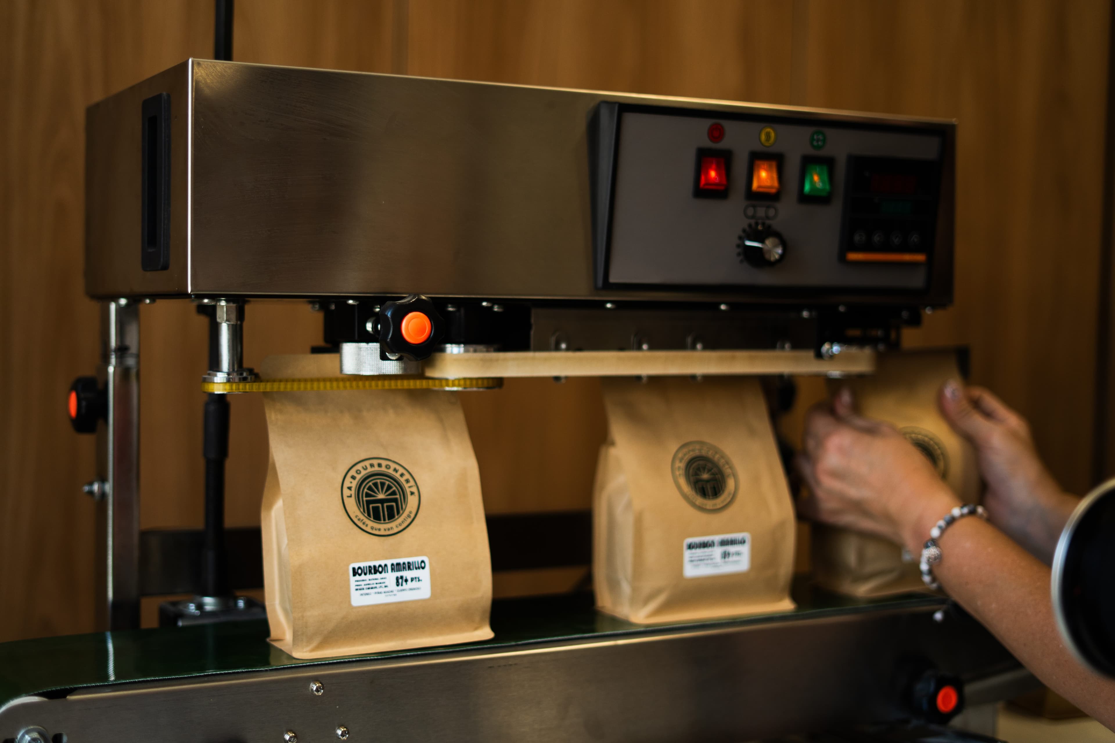 Máquina de sellado procesando bolsas de papel de café Bourbon Amarillo en una cinta transportadora.